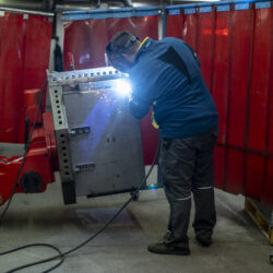Employee welding a large piece of sheet metal