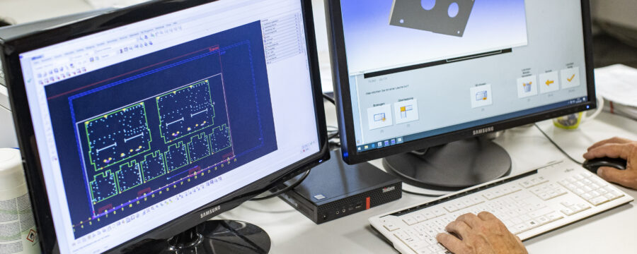 Employee sits in front of two monitors on which CAD designs can be seen