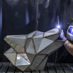 Schweißarbeit an der metallischen Darstellung des Logo-Signets