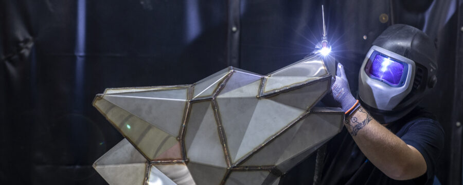 Schweißarbeit an der metallischen Darstellung des Logo-Signets